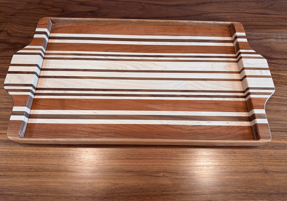 Wooden tray with striped pattern on a wooden surface.